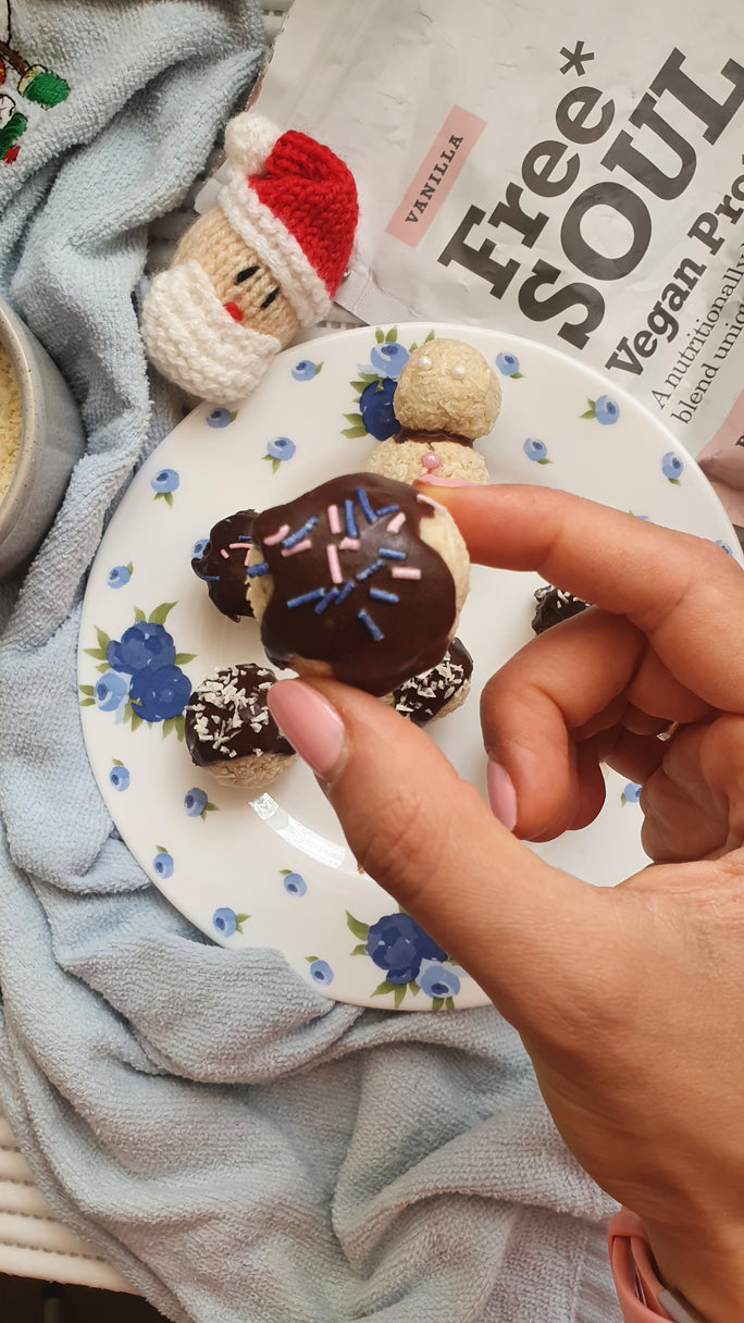 Hand holding a protein ball topped with chocolate and sprinkles