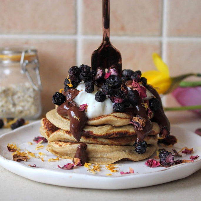 Stack of three pancakes with chocolate drizzle, cream and a fork on top
