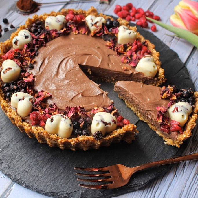 Chocolate tart with a biscuit crust and dried rose petals around the edge