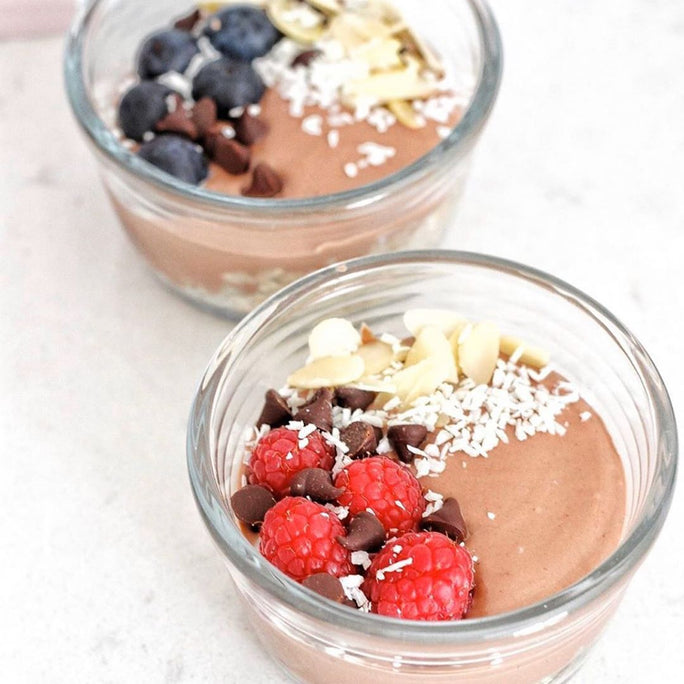 Two glass bowls topped with chocolate pudding, raspberries, almonds, chocolate chips and coconutTwo glass bowls topped with chocolate pudding, raspberries, almonds, chocolate chips and coconut