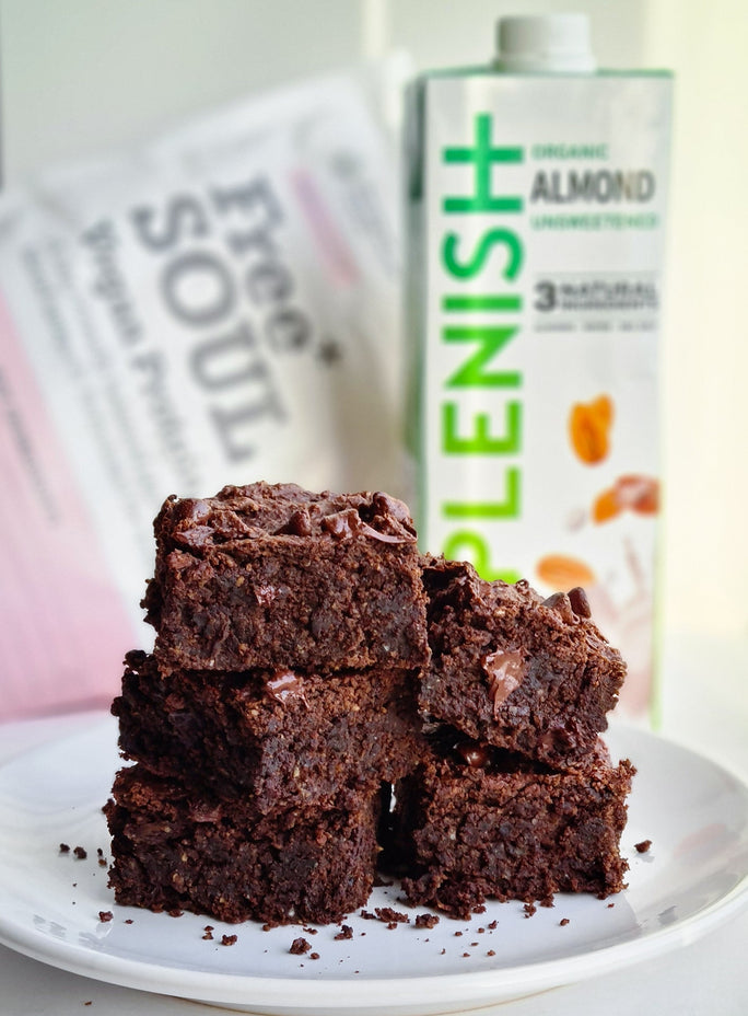 Gooey stack of brownies next to Plenish Almond Milk and Free Soul protein powder