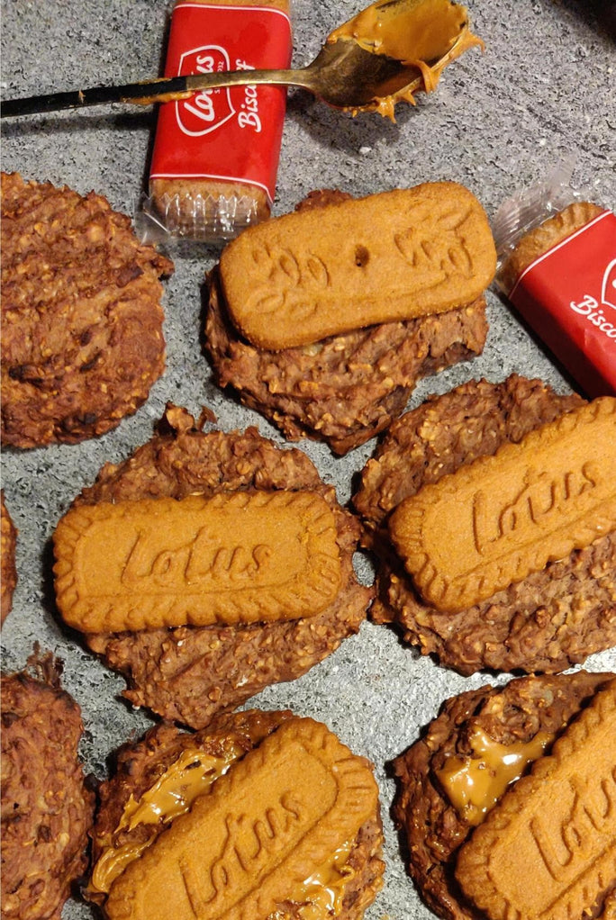 Brown cookies topped with Lotus biscuits next to a spoon with Biscoff spread