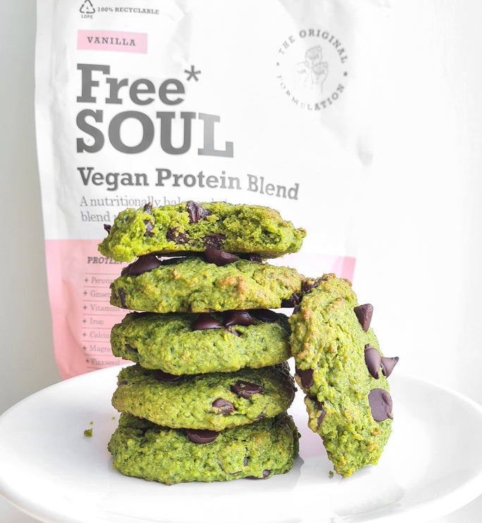 a stack of spinach protein cookies in front of a free soul vegan protein blend bag 