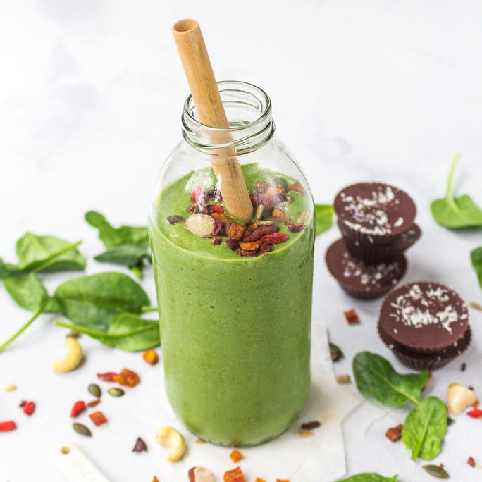 a bottle of refreshing green smoothie with a bamboo straw 