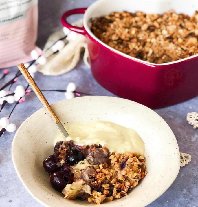 A white bowl filled with granola, blueberries and yoghurt