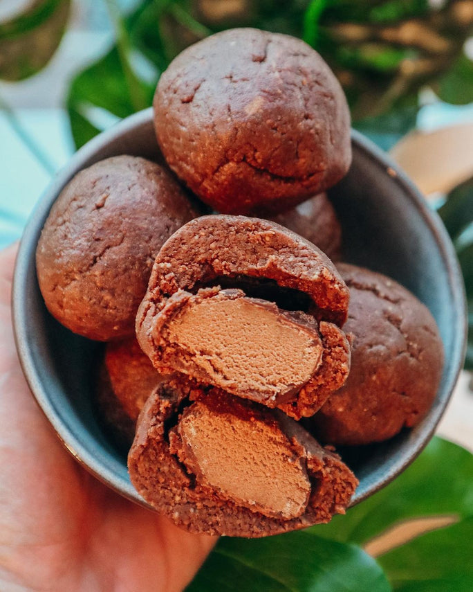 A blue bowl of large choaolte protein balls with a creamy filling
