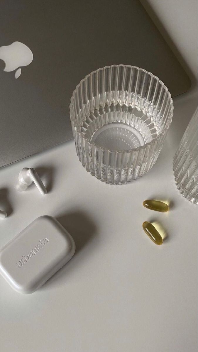 Supplements laid out on a white table next to a glass of water