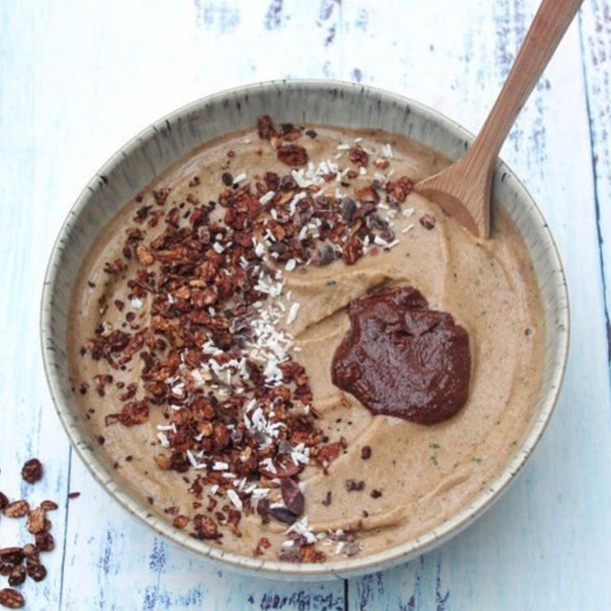 Chocolate smoothie in a bowl with a wooden spoon