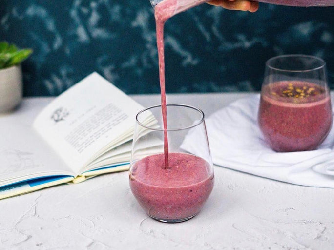 Purple smoothie on a white marble table next to an open book