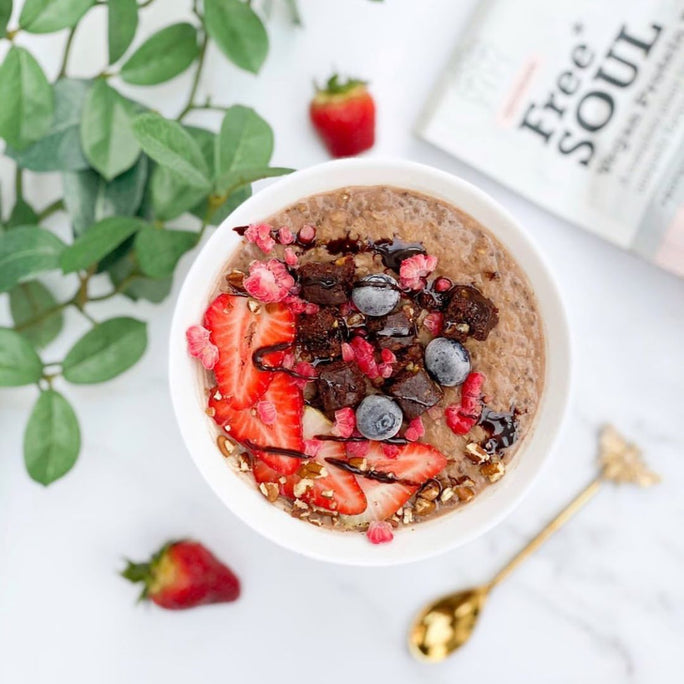 A bowl of oats with strawberries, blueberries and chocolate drizzle