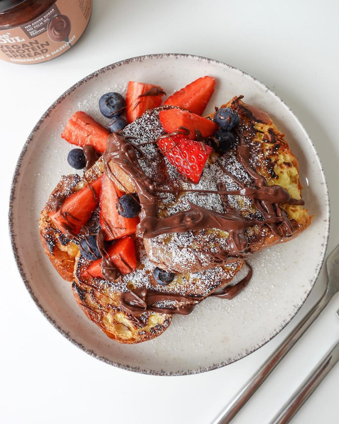 A plate of chocolate protein french toast with fresh strawberries and blueberries