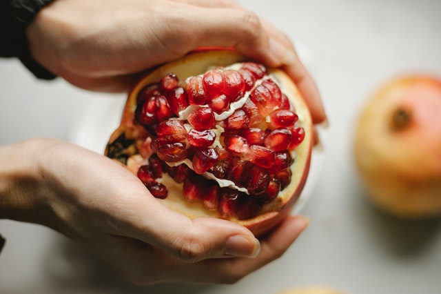 Close up of a hand holding a pomegranate