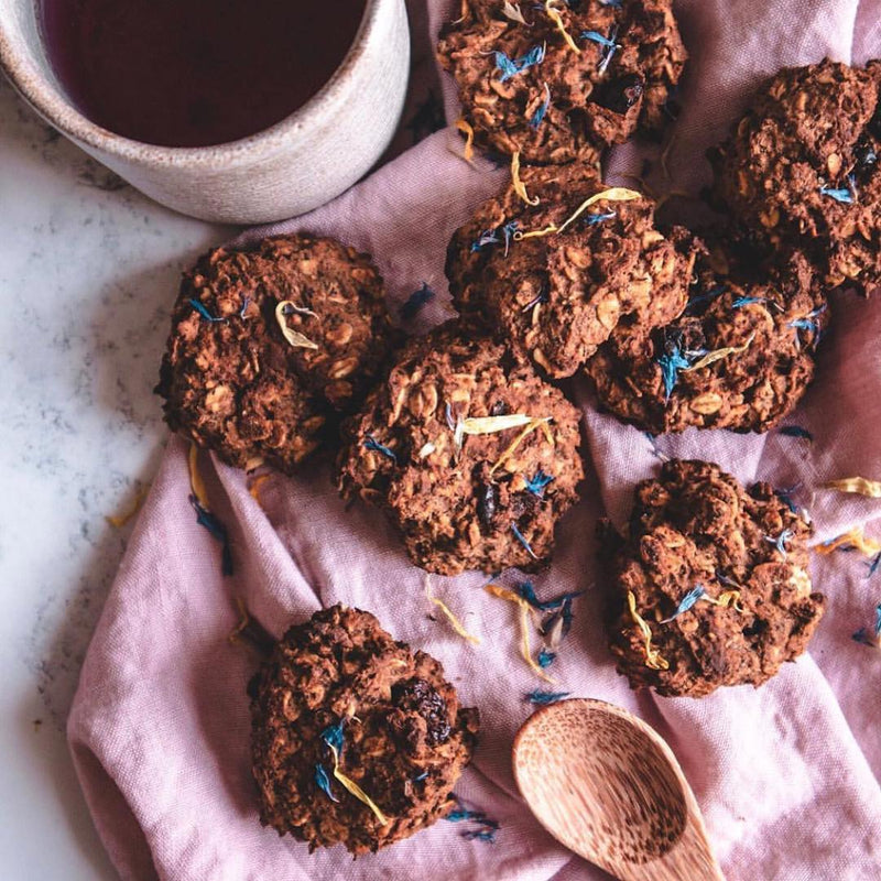 Small oat bites on a light pink kitchen towel next to a wooden spoon