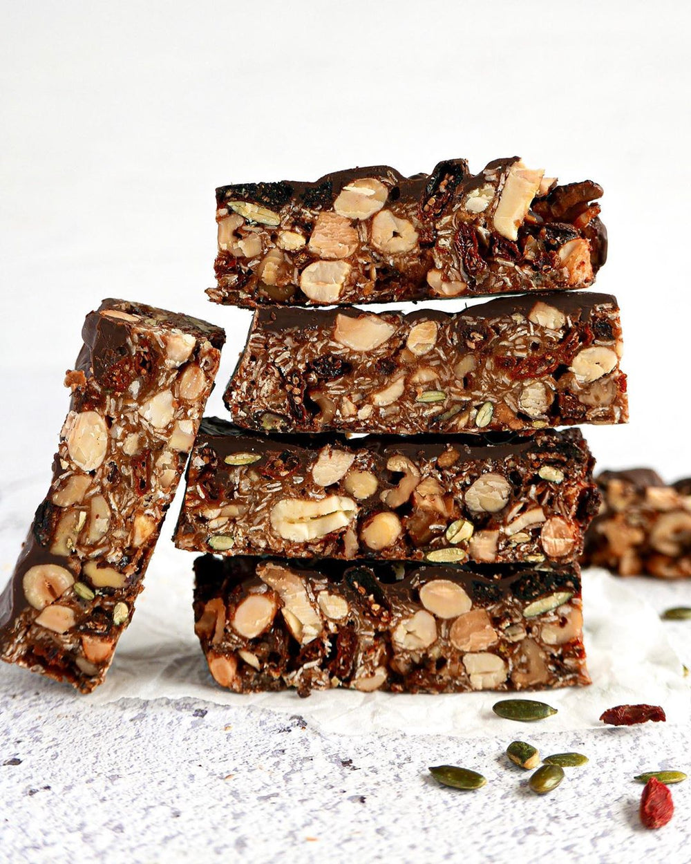 Stacked flapjack slices on a white baking paper with nuts at the front