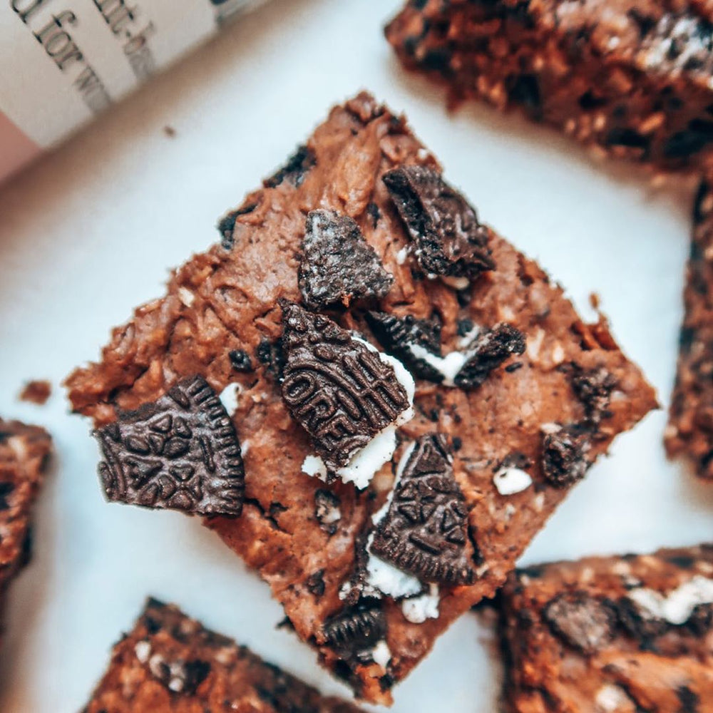 Brownies topped with crushed oreo cookies next to Free Soul protein powder