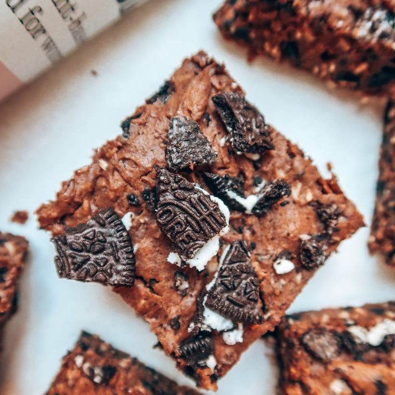 Brownies topped with crushed oreo cookies next to Free Soul protein powder