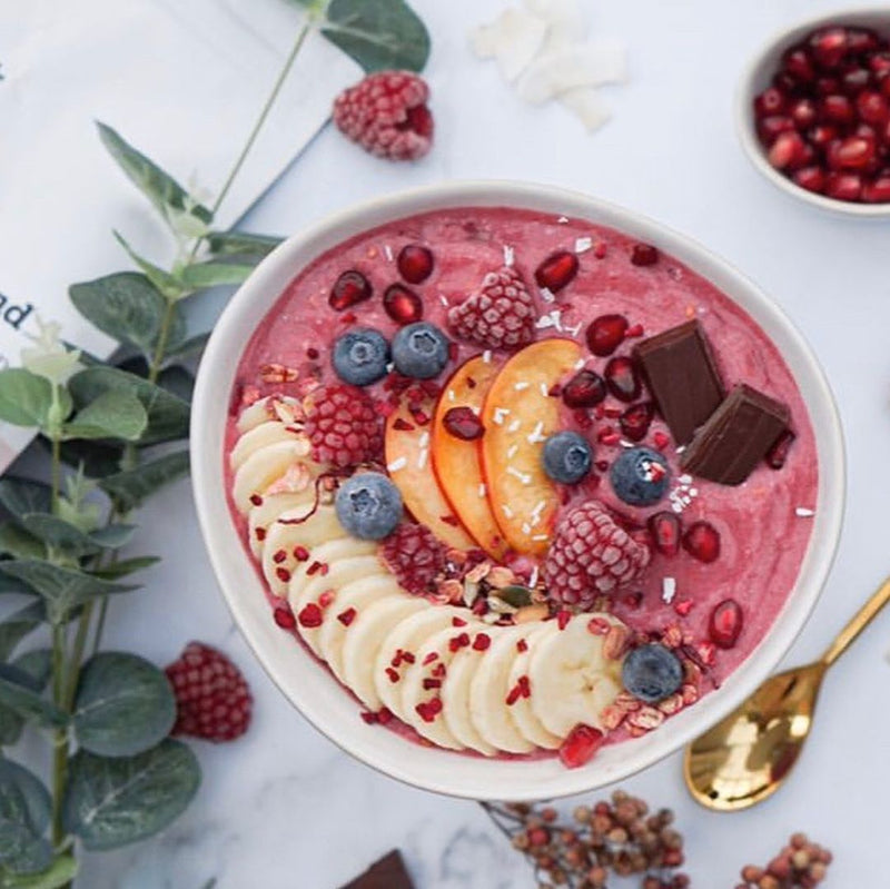 Purple smoothie on a white marble table next to an open book