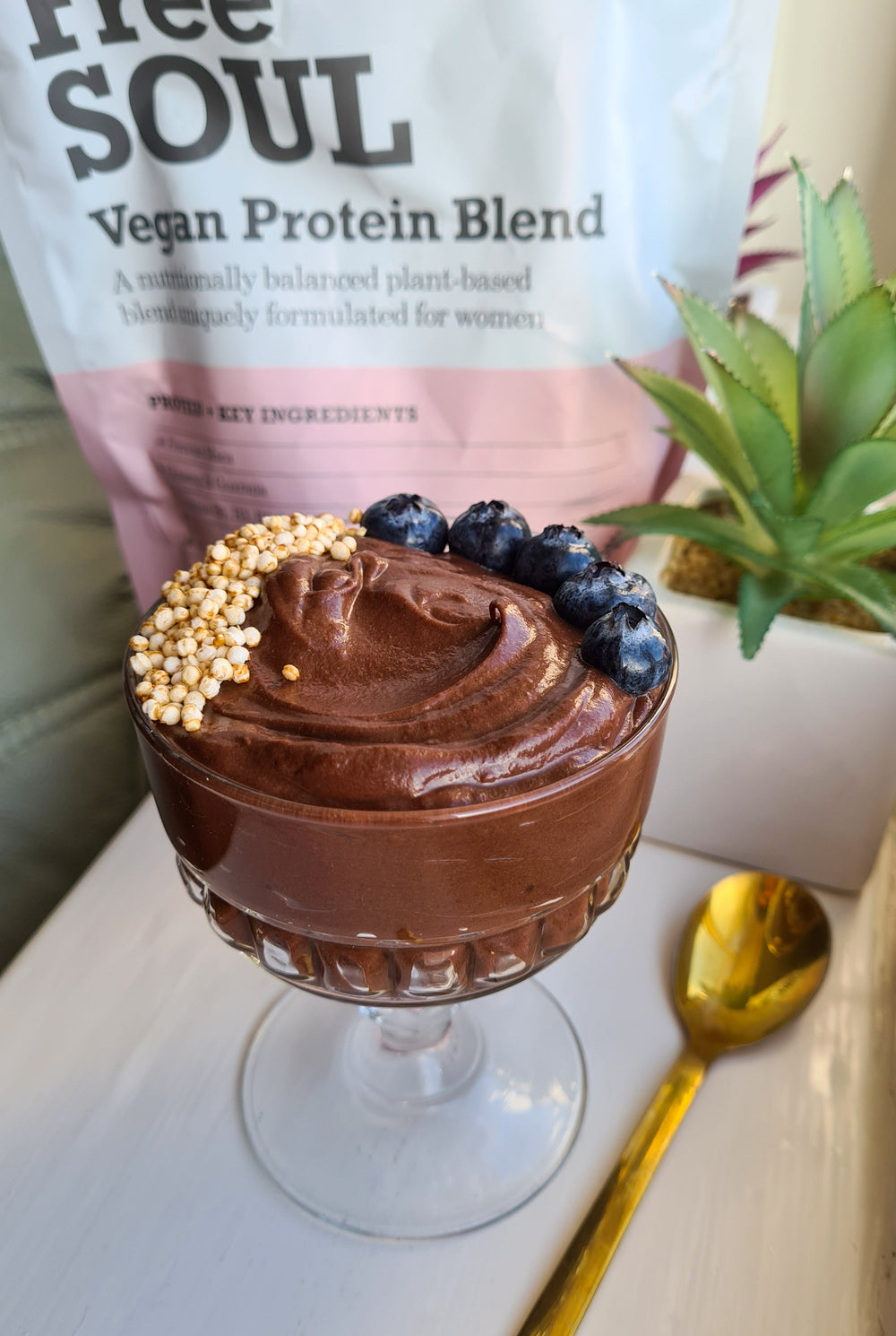 Glass tulip bowl of chocolate pudding topped with blueberries