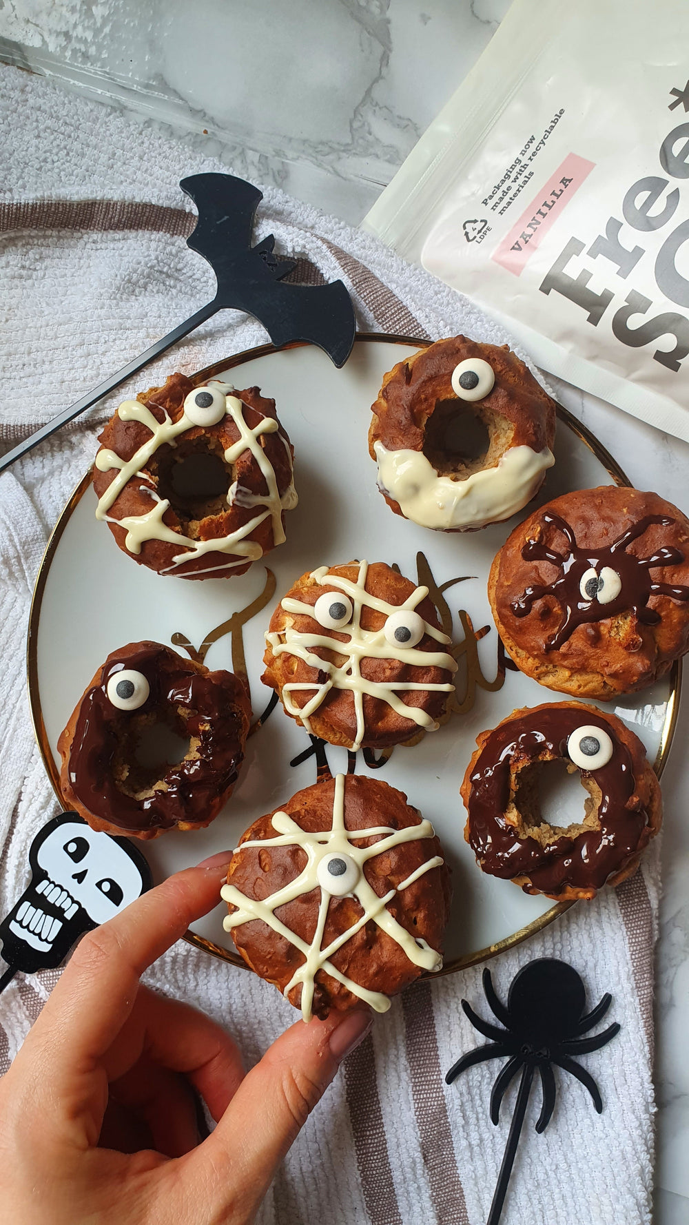 A plate of donuts with googley eyes next to halloween decorations
