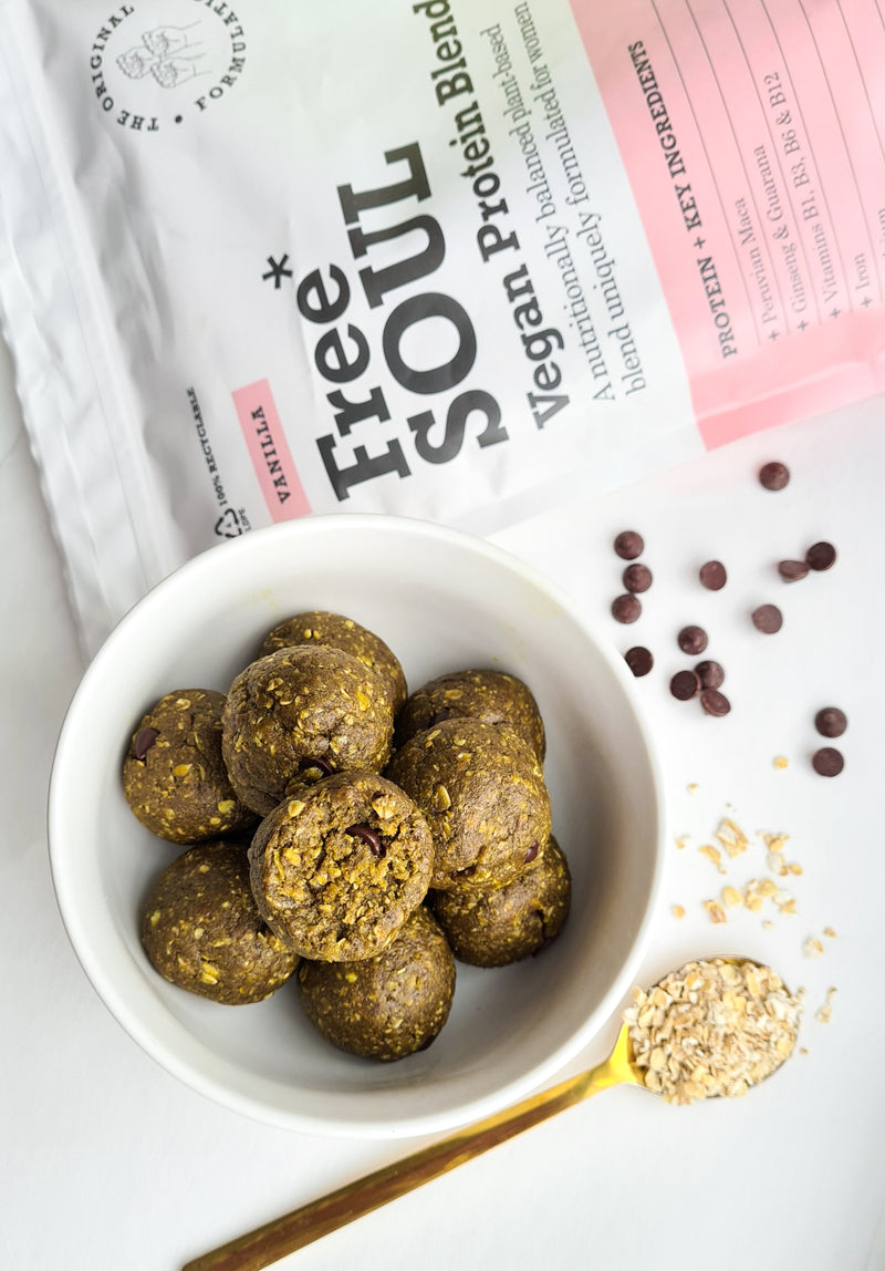Free Soul vanilla vegan protein balls in a white bowl next to sprinkled chocolate, nuts, spoon and free soul packaging