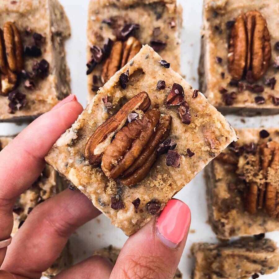 Close up of a hand holding a white brownie topped with a whole walnut