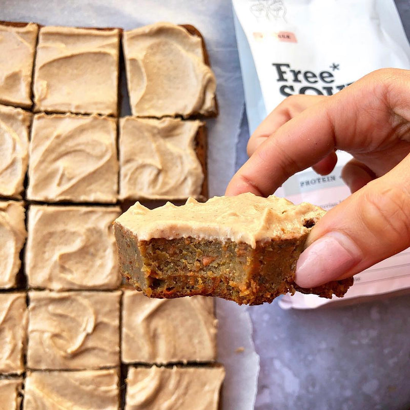 Dessert bars topped with frosting next to Free Soul protein