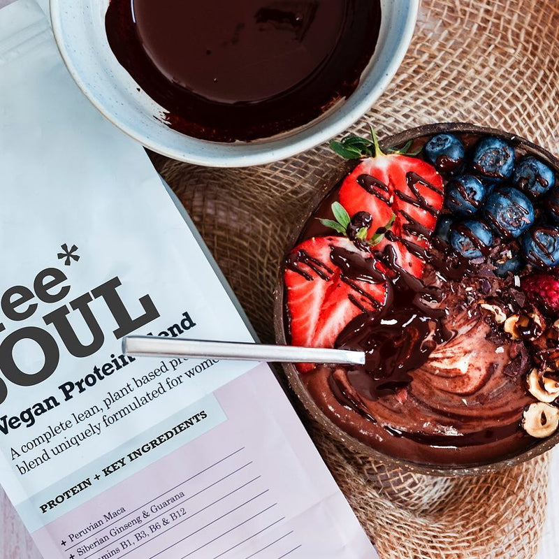 A silver spoon resting in a coocnut bowl filled with a chocolate smoothie