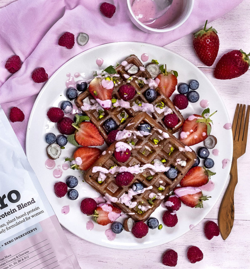 Chocolate waddles topped with fruit sauce, berries and green seeds
