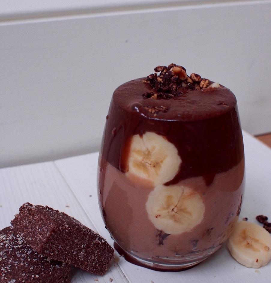 a glass of chocolate protein smoothie with banana and pomegranate