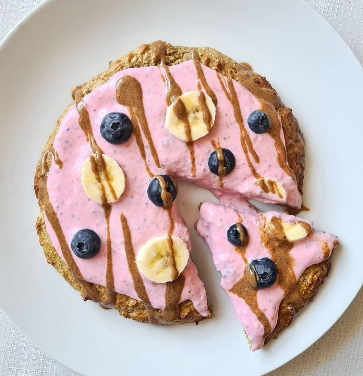 A plate of oats topped with pink smoothie, strawberries and blueberries