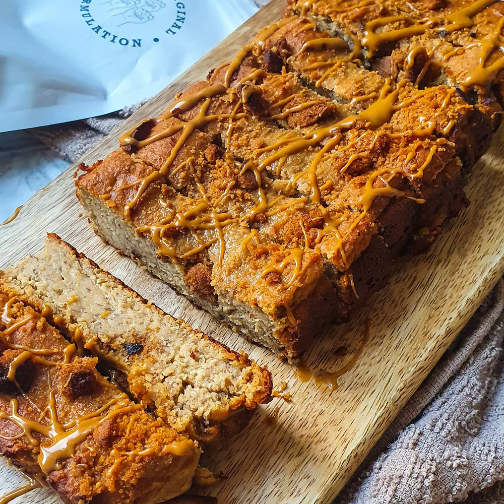 A loaf drizzled with biscoff crumbs and spread next to a bag of Free Soul protein