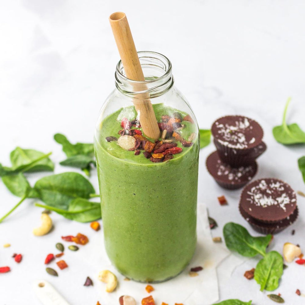 a bottle of refreshing green smoothie with a bamboo straw 