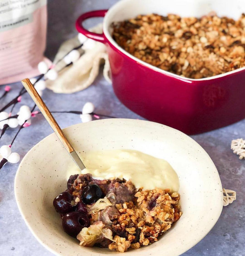 A white bowl filled with granola, blueberries and yoghurt