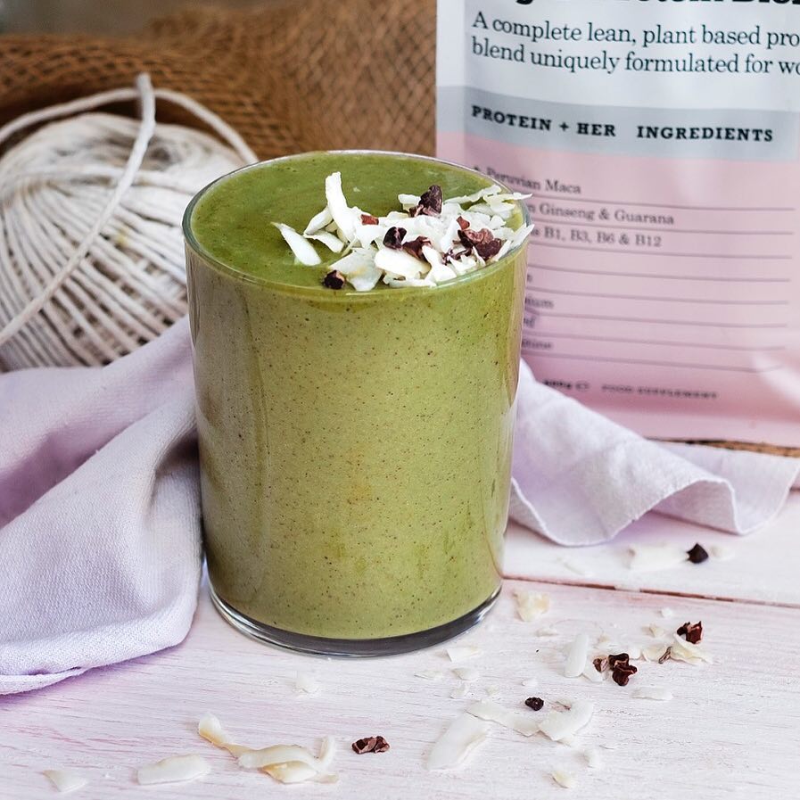 a glass of green 'slime' smoothie topped with coconut flakes