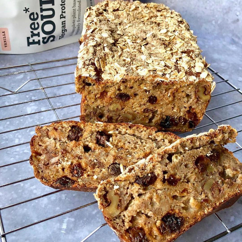 A loaf topped with oats on a silver cooling rack