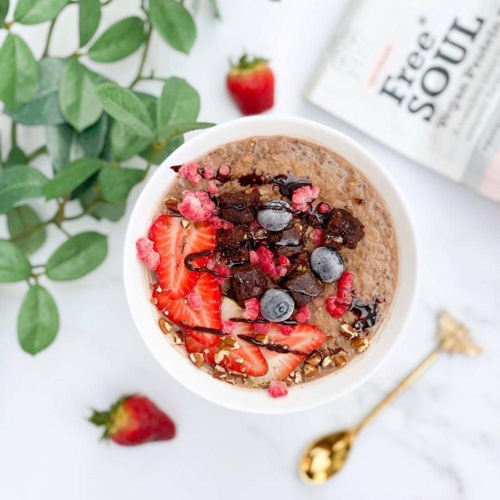 A bowl of oats with strawberries, blueberries and chocolate drizzle