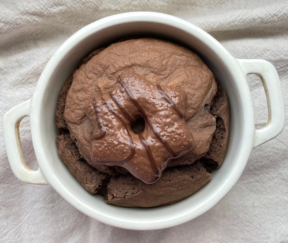 Chocolate dessert in a white pot with handles topped with a lebkuchen