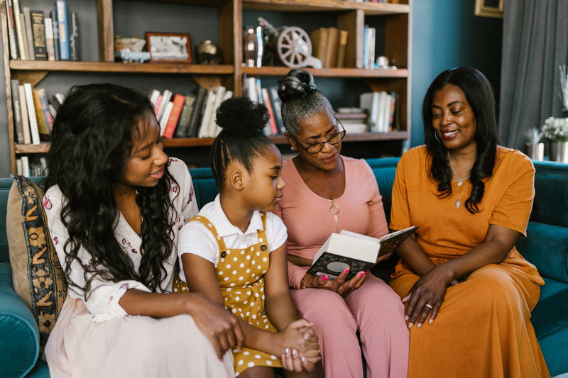 A family sat on a blue veltet couch reading a book
